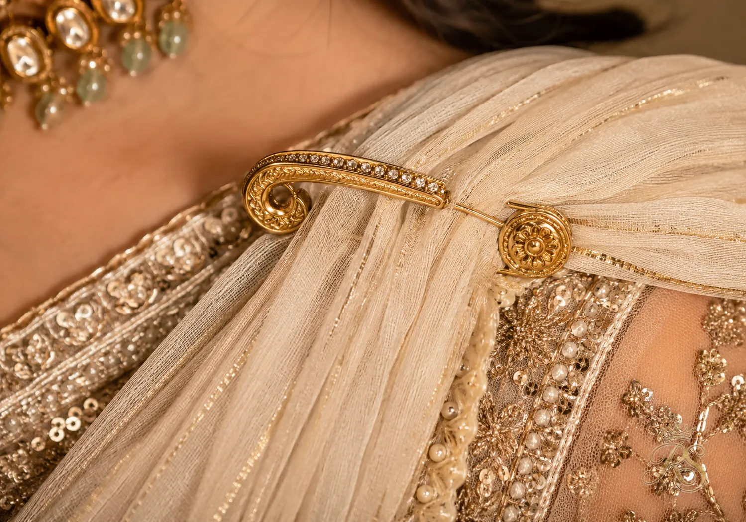 Close-up of shoulder pin securing a pleated bridal dupatta