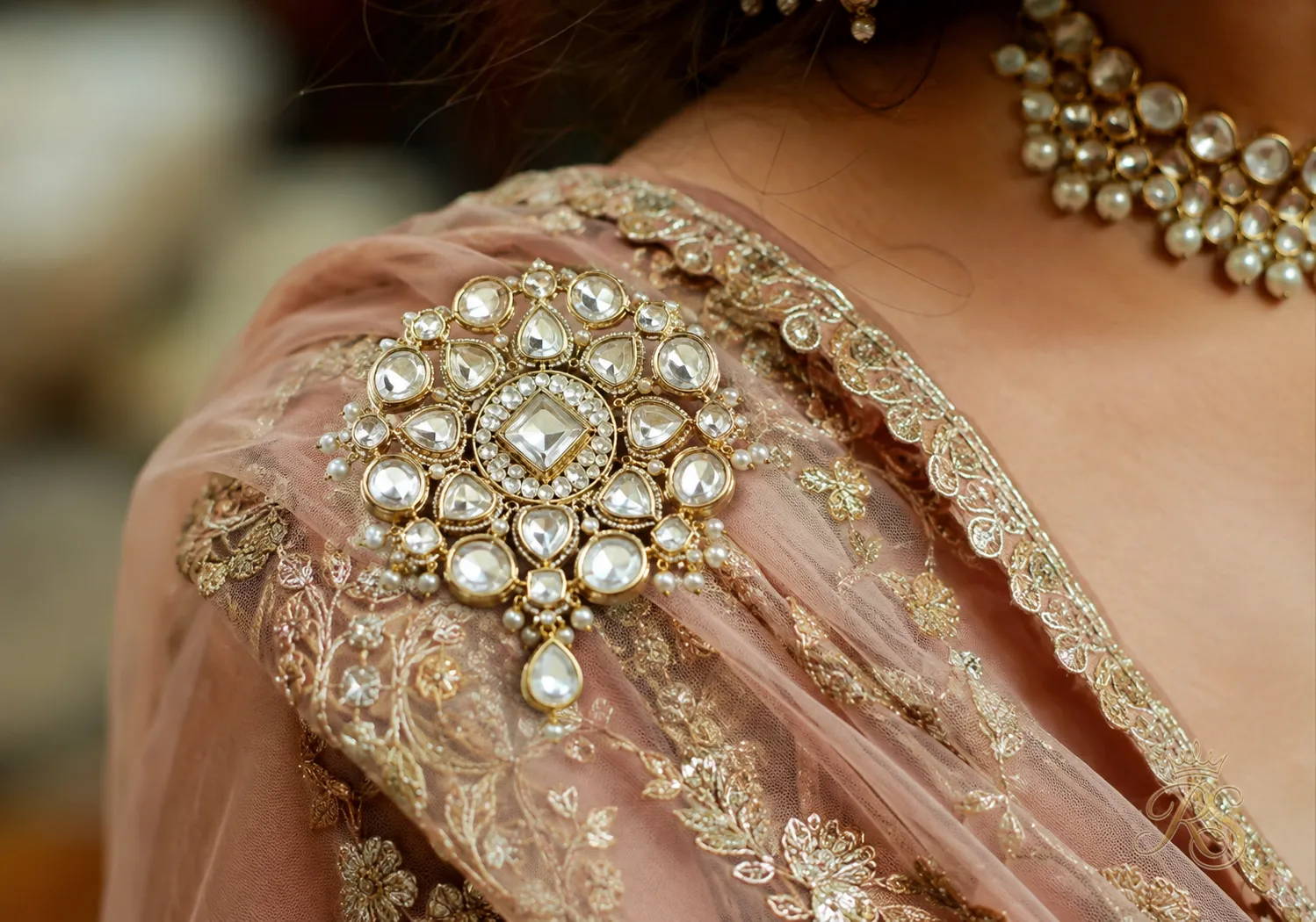 Close-up of a jeweled brooch pinning a bridal dupatta at the shoulder