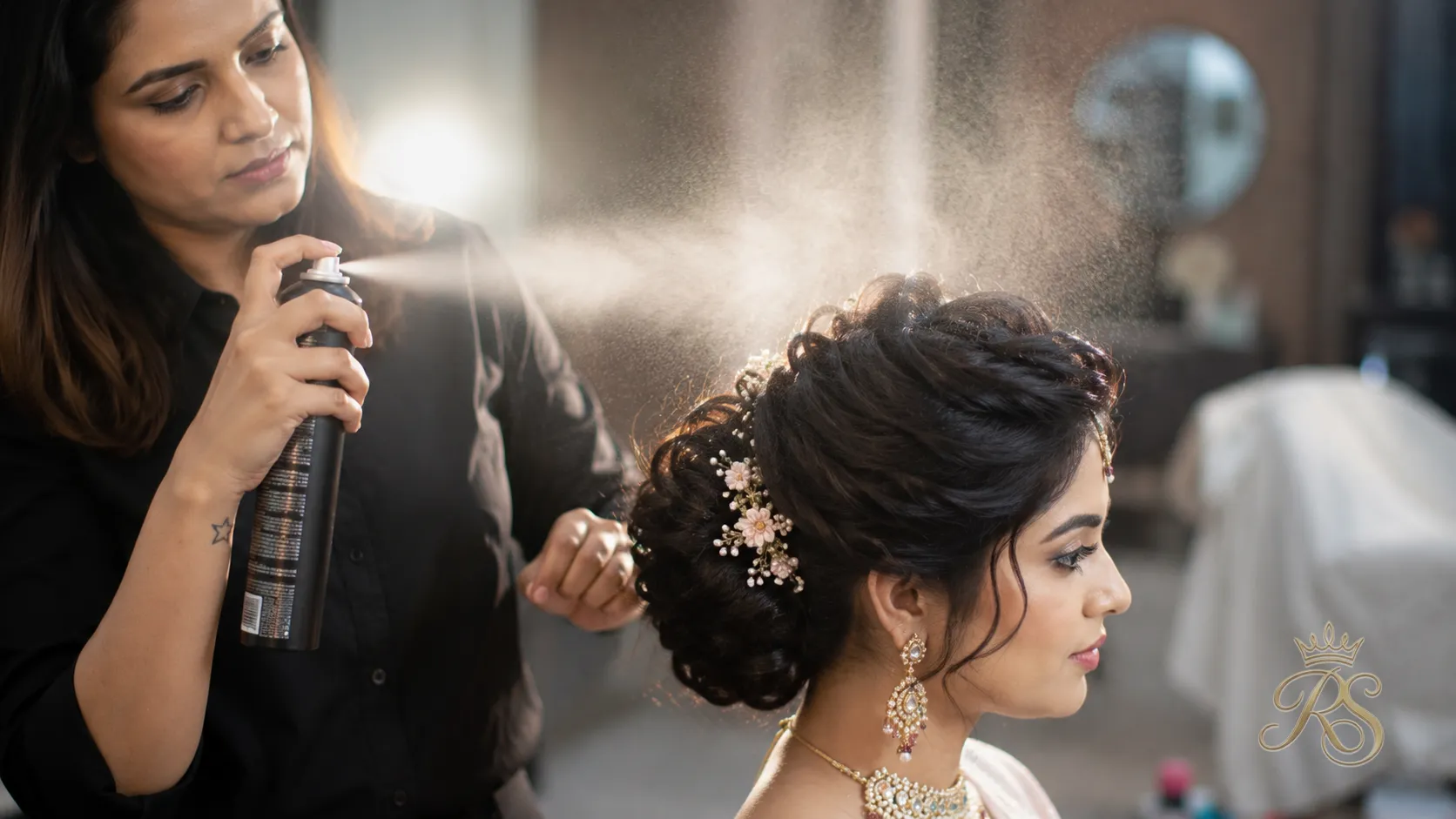 Hairstylist applying a fine-mist setting hairspray to lock a bridal updo