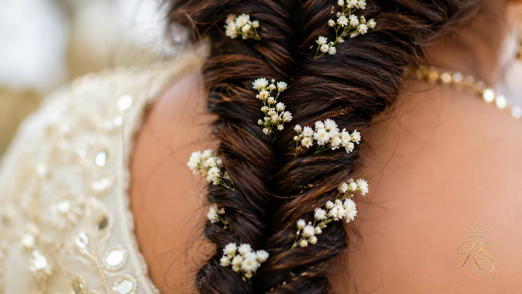 Close-up of a fishtail braid decorated with small flowers for mehendi