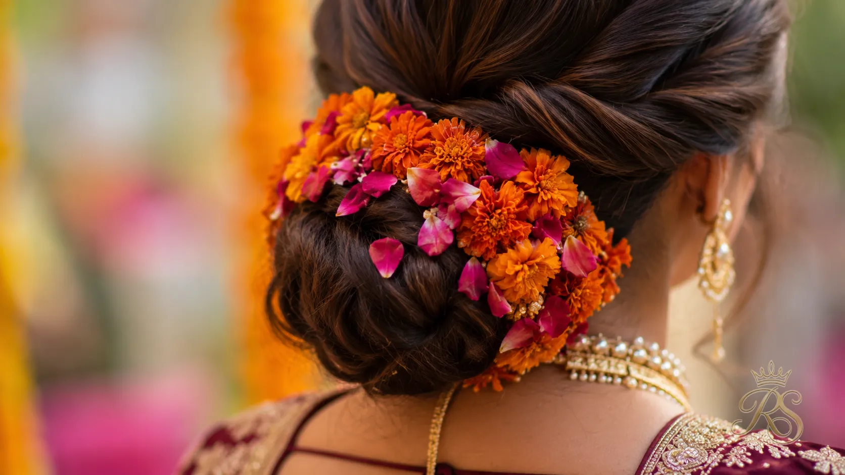 Low bun tucked with marigold and rose petals for a mehendi look