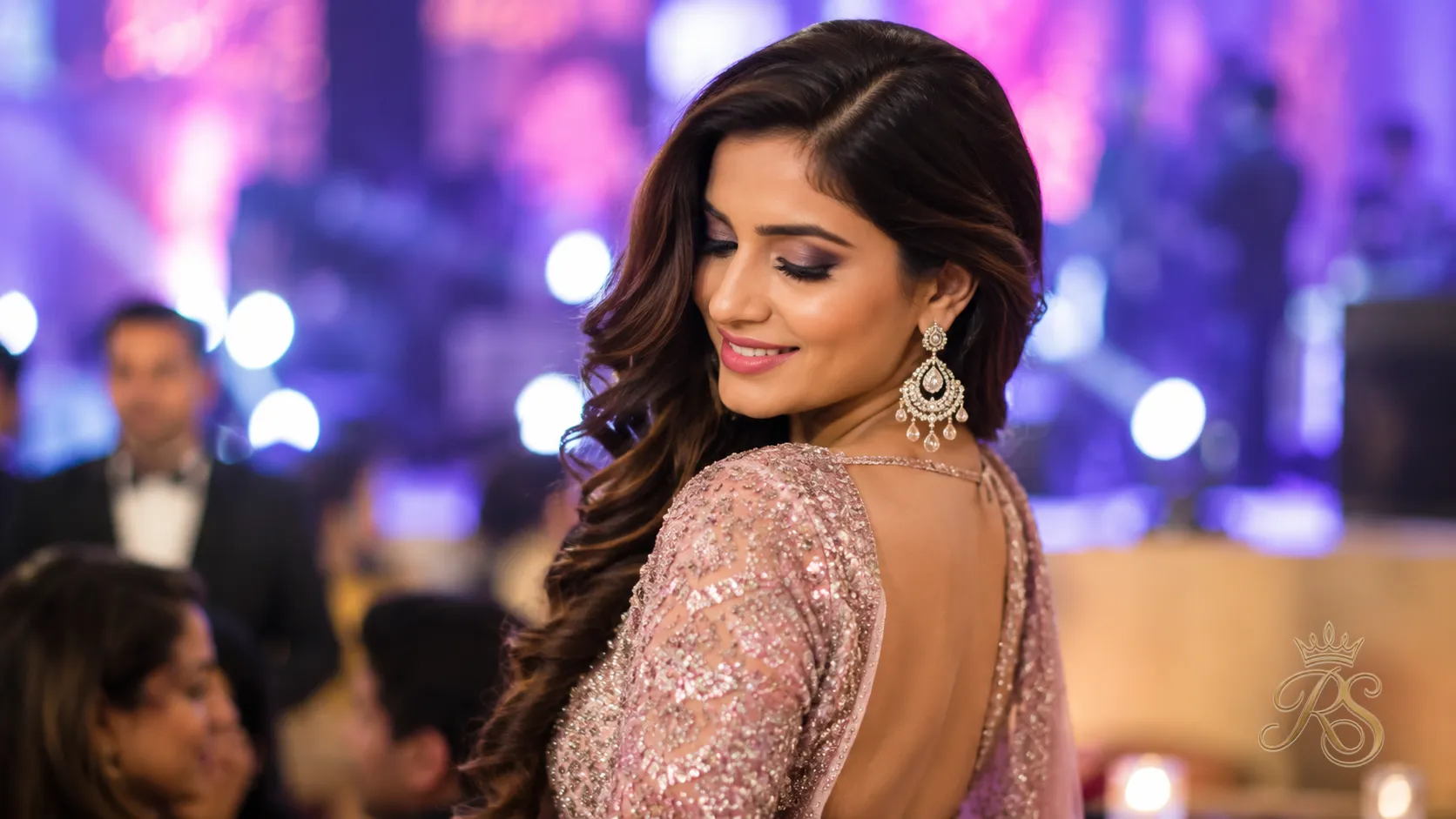 Bride with voluminous glamorous waves and a deep side part at sangeet party