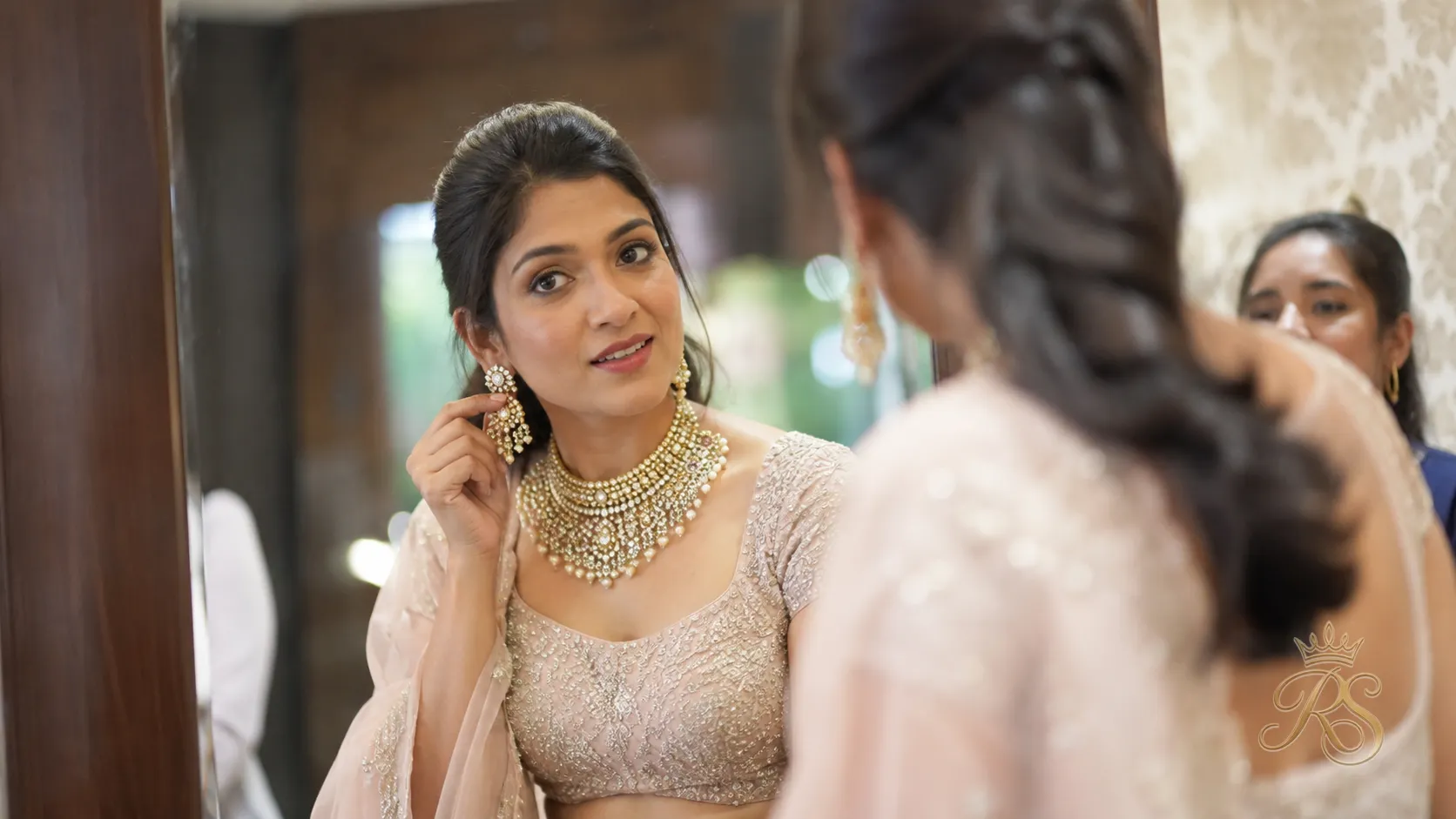 Bride trying on different bridal jewellery pieces in front of a mirror during a fitting