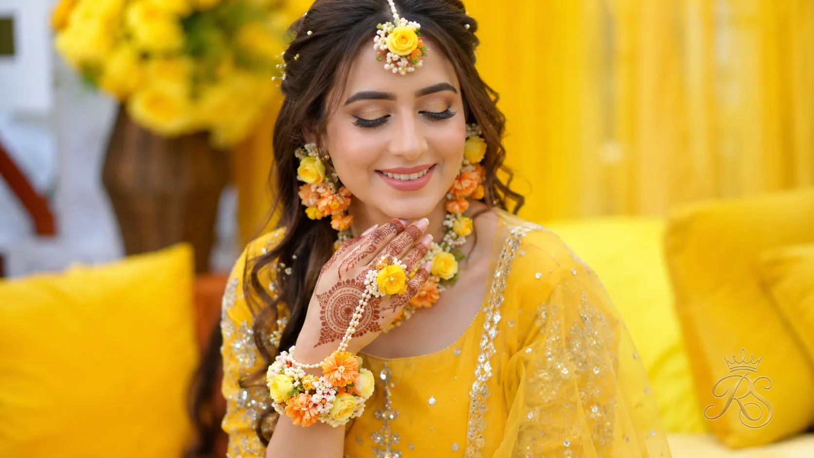 Bride at mehendi ceremony wearing floral jewellery and haathphool hand harness