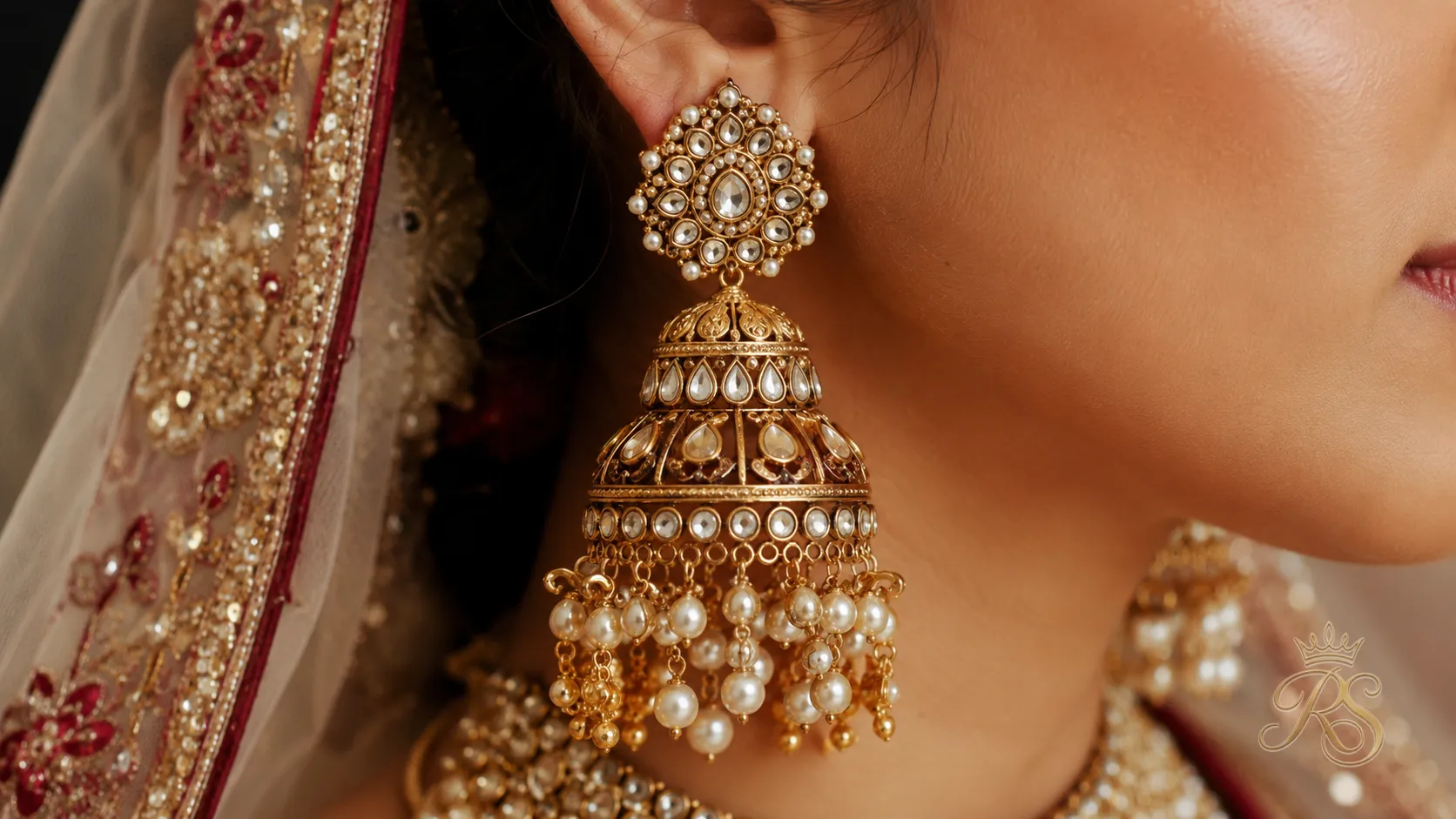 Close-up of oversized statement bridal earrings with hanging pearl and gold drops