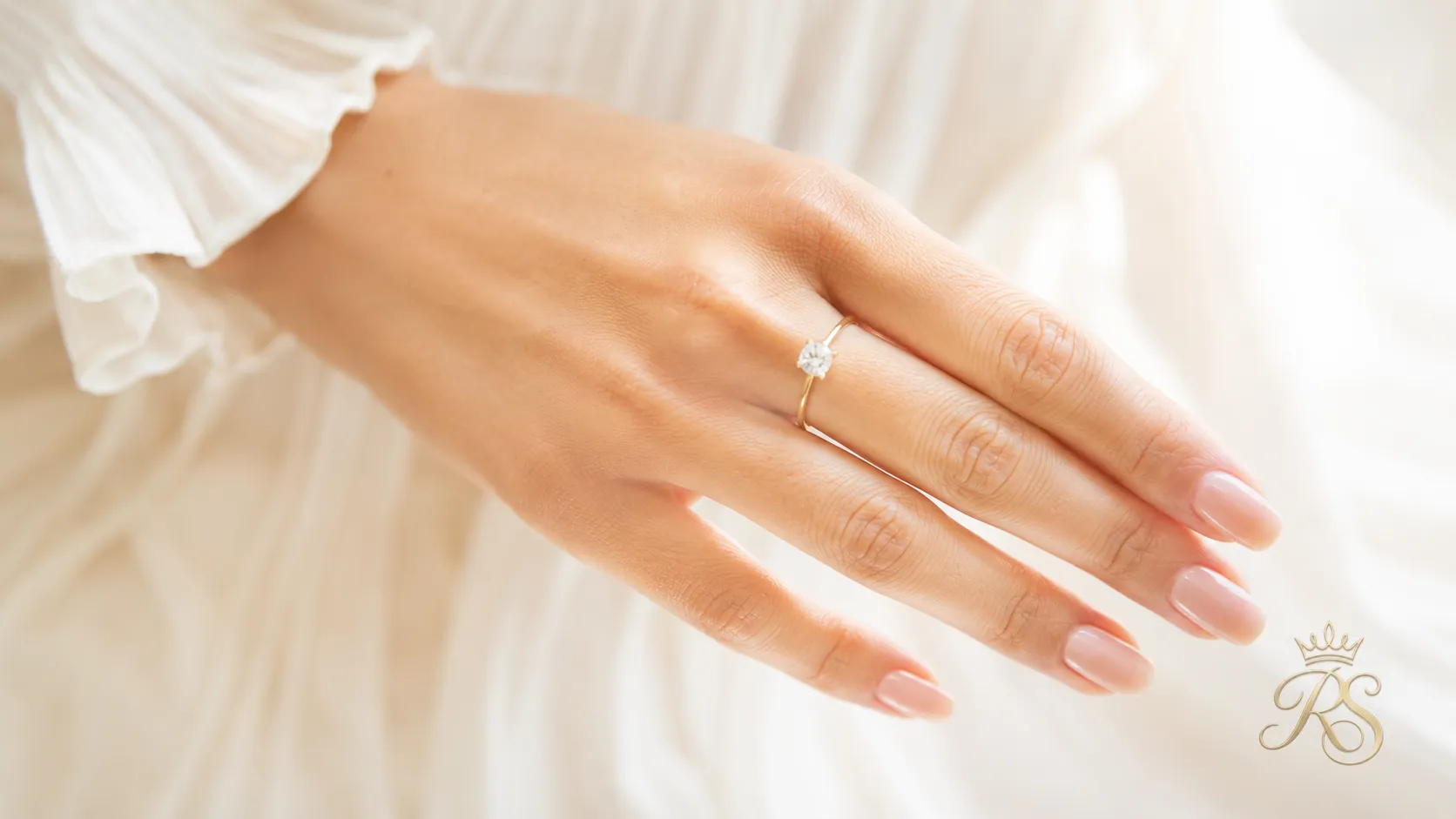 Delicate engagement ring fitted on a slender finger, photographed from above
