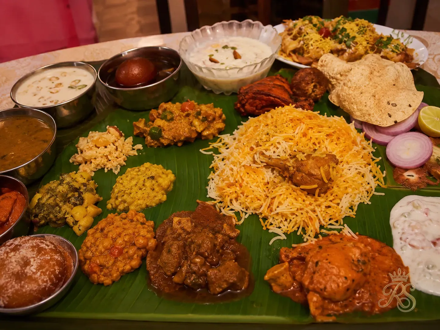 Elaborate Indian wedding food spread with biryani, curries, chaat and desserts laid on banana leaves