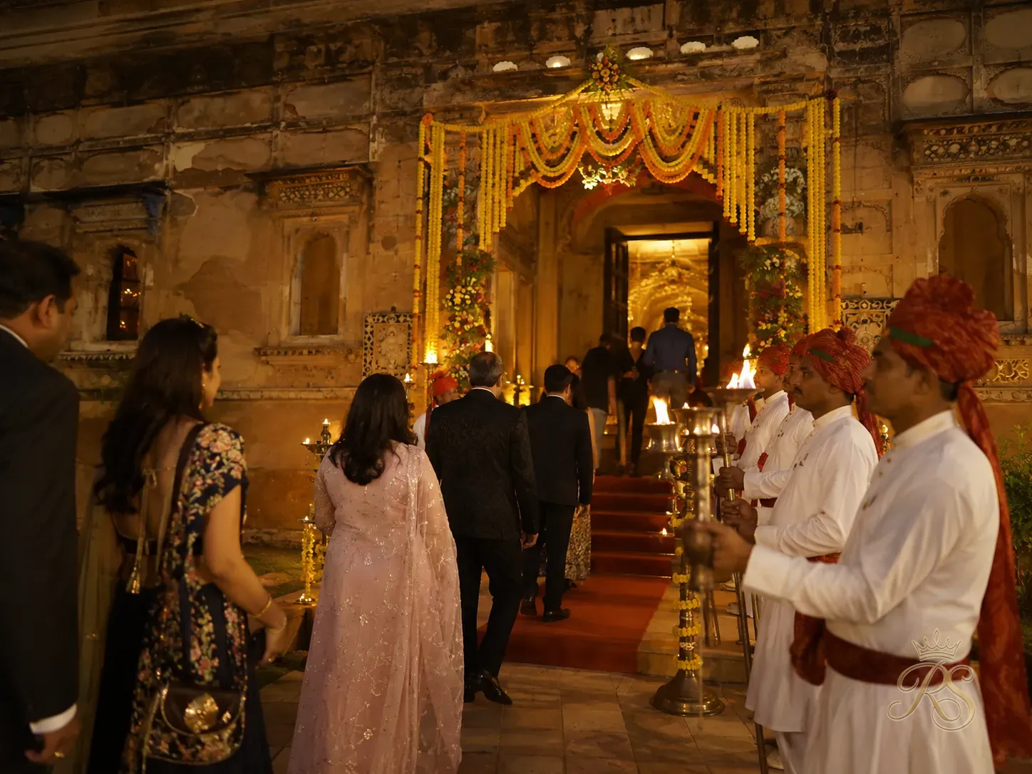 Wedding guests arriving at a heritage venue with welcome garlands and traditional torches