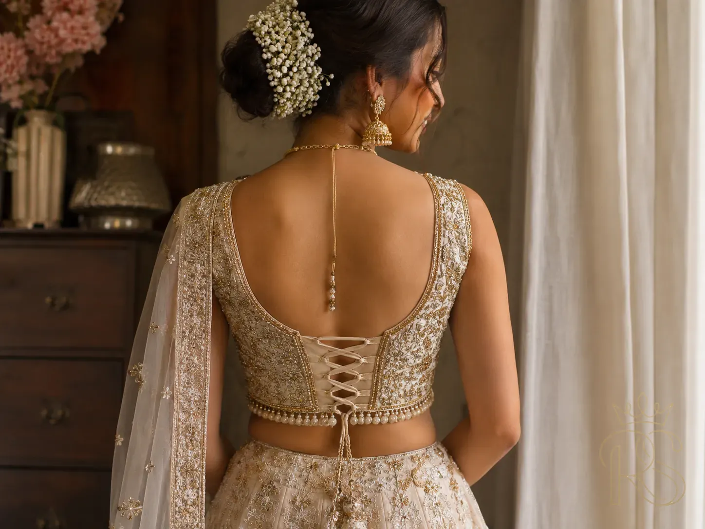 Indian bride wearing a deep-back corset blouse in ivory silk with intricate gold zardozi embroidery, photographed from the back, editorial bridal photography, soft warm light, lehenga skirt partially visible