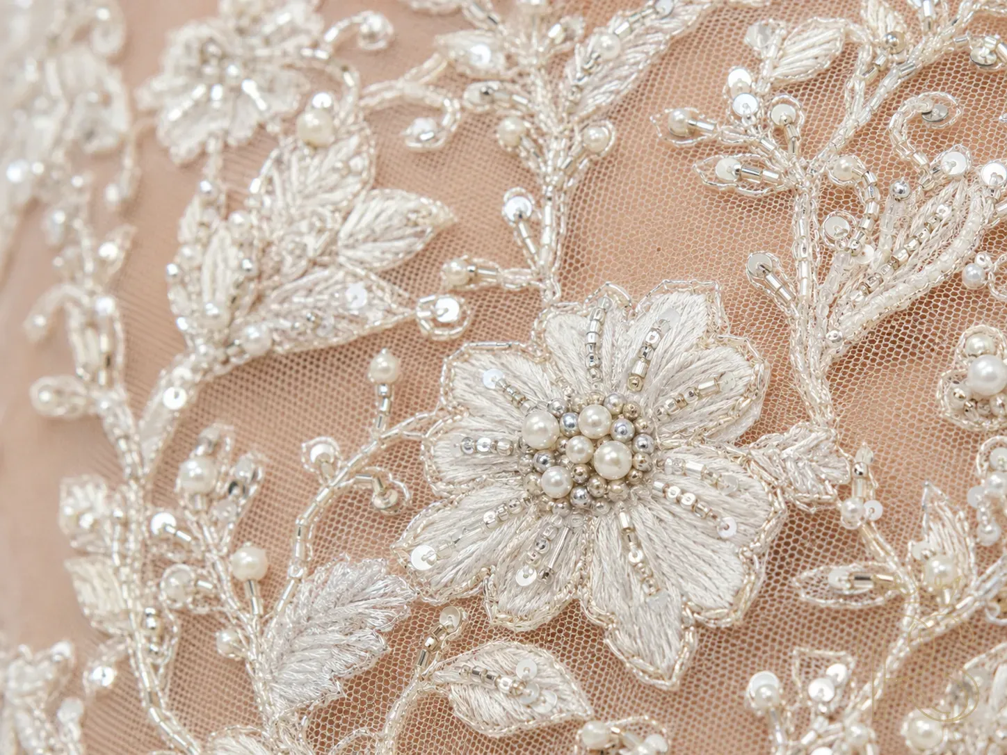 Extreme close-up of sheer net bridal blouse embroidered with tiny silver sequins, seed pearls, and floral threadwork on transparent fabric, macro fashion photography, clean background
