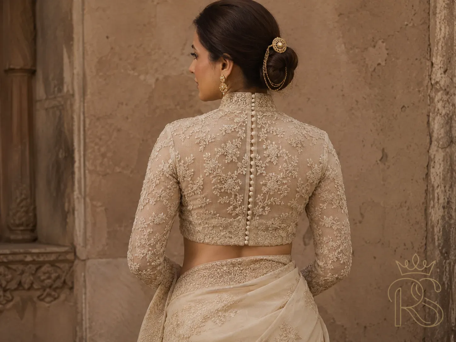 Back view of Indian bride in high-neck Victorian bridal blouse with a row of fabric-covered buttons down the back and full embroidered sleeves, editorial fashion photography, muted stone wall background