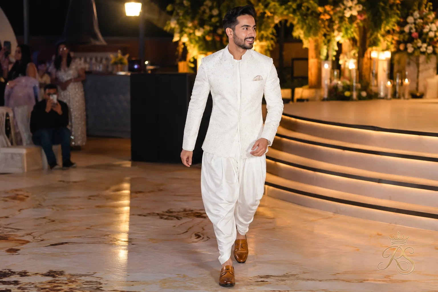 Groom wearing tailored dhoti pants with a contemporary short jacket at a sangeet function