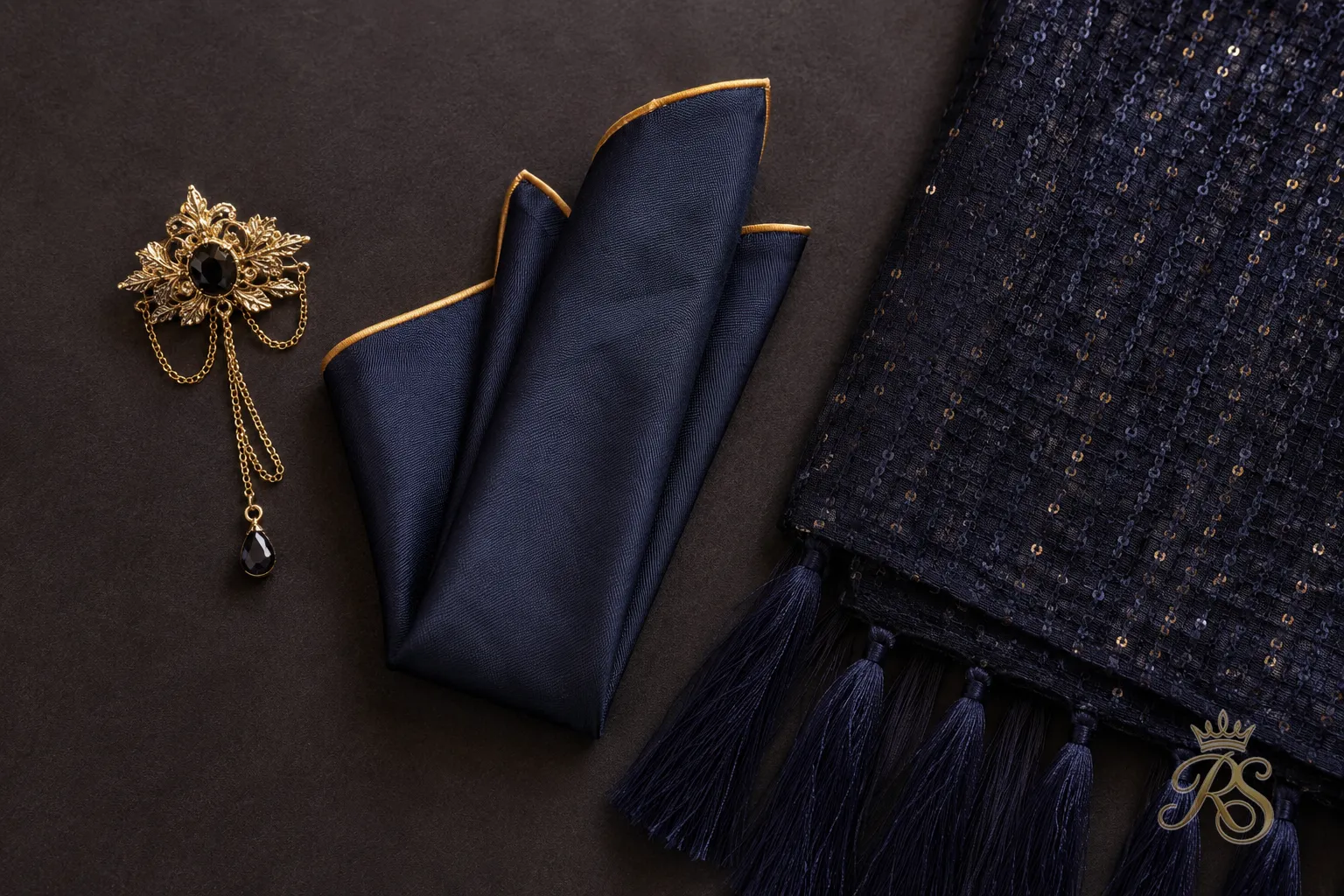 Flatlay of groom sangeet accessories including a brooch, pocket square, and stole