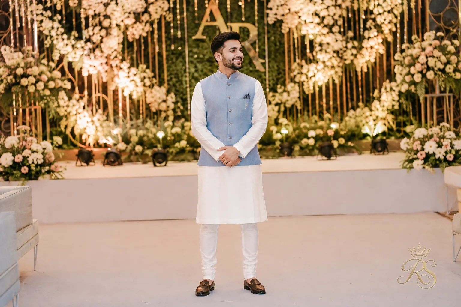 Groom in a pastel blue Nehru jacket and white kurta at an evening sangeet function