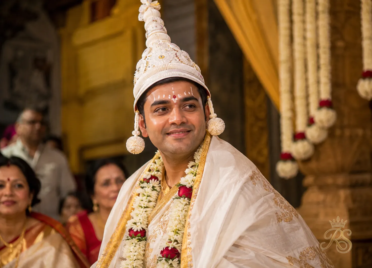 Bengali groom in a white and gold dhoti with a conical topor headdress