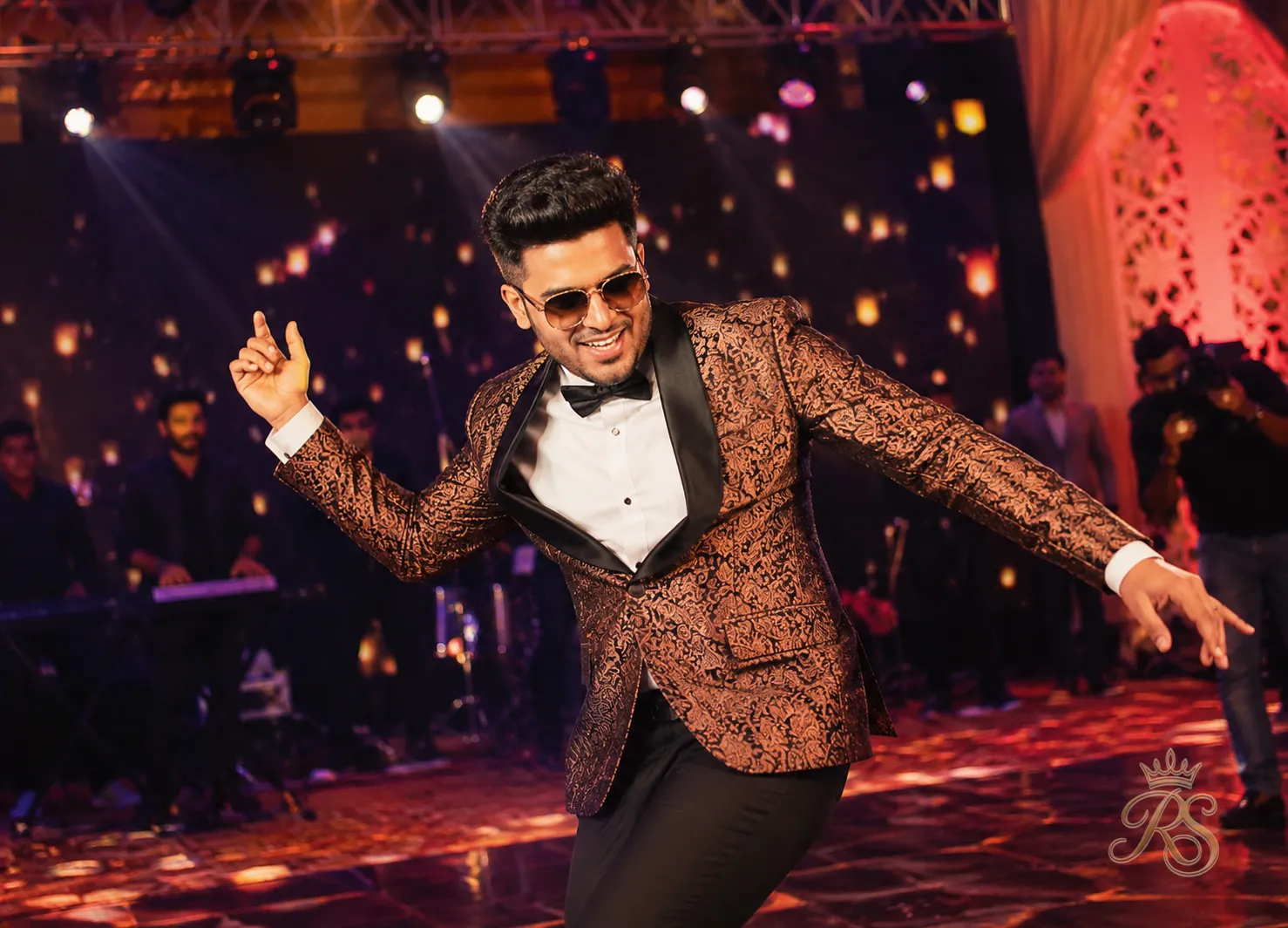 Groom in a printed silk jacket and trousers dancing at his sangeet night function