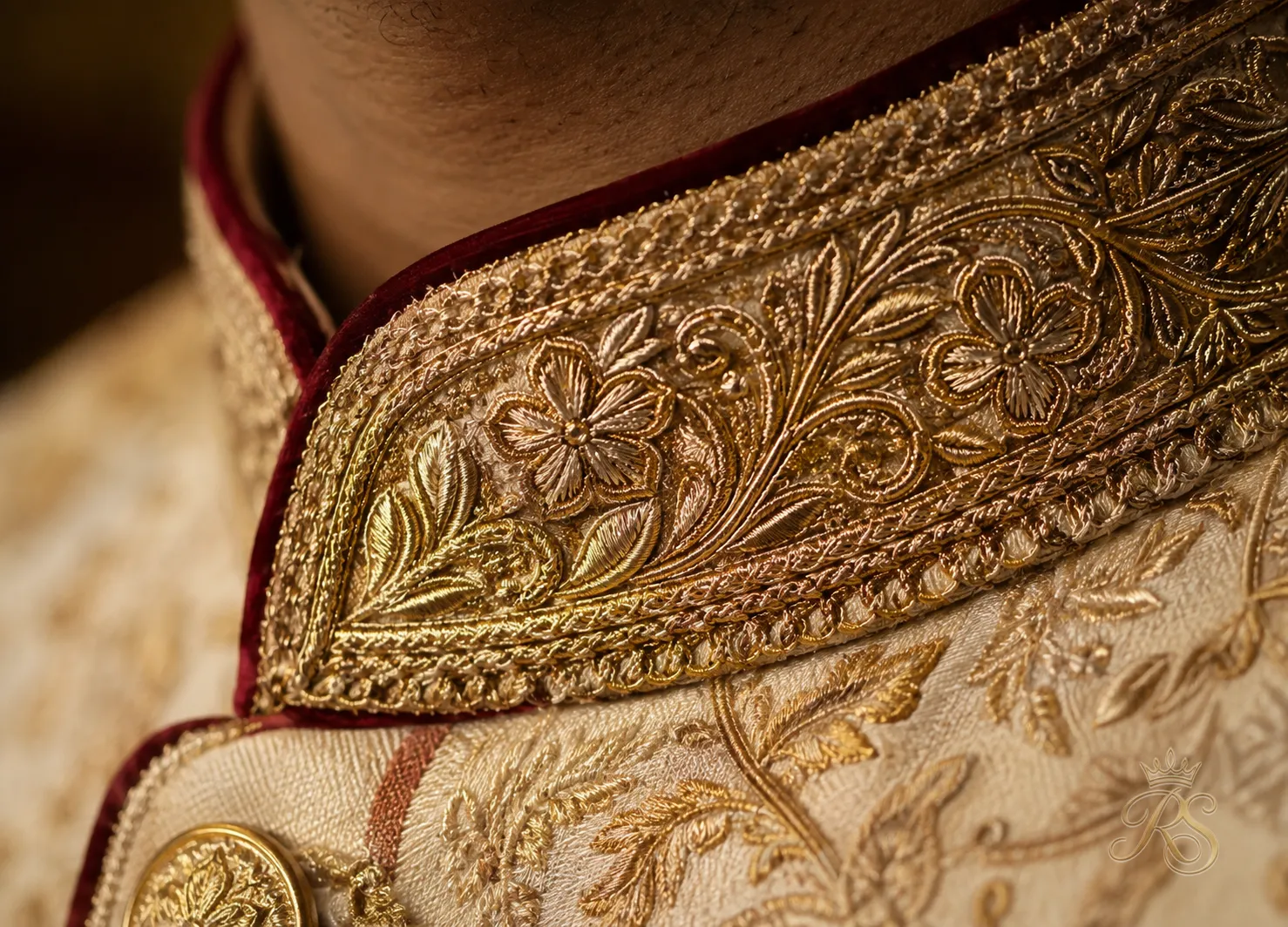 Close-up of intricate gold zari embroidery on a groom's sherwani collar