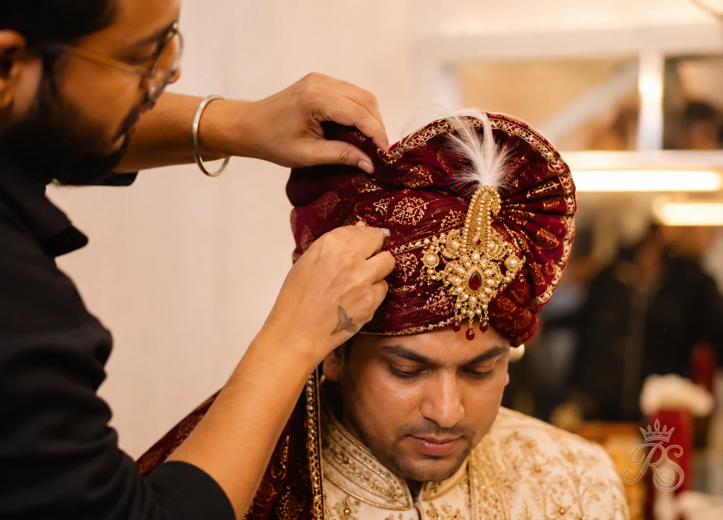 Close-up of a groom's turban being tied by a professional stylist