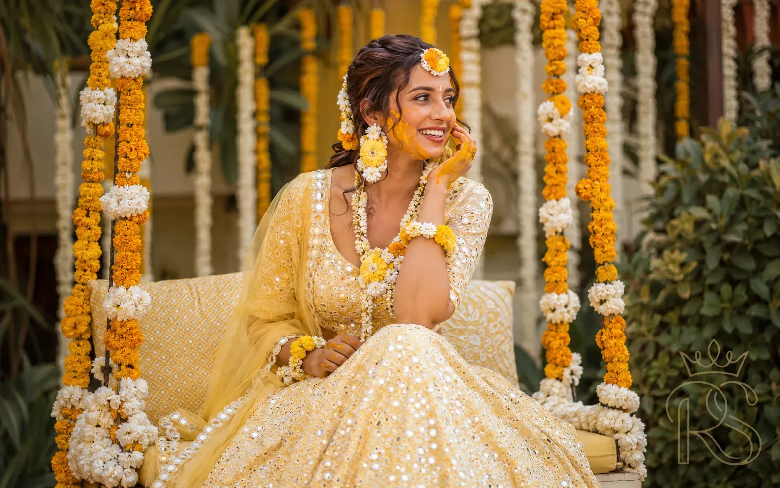 Indian bride in yellow chikankari lehenga with marigold flower jewellery at Haldi ceremony