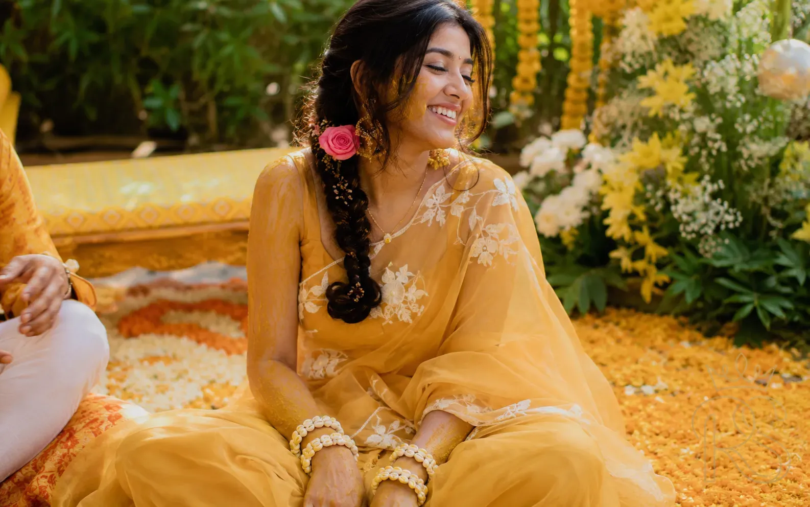 Indian bride wearing a yellow organza saree with white embroidery and flower accessories at Haldi ceremony in morning light