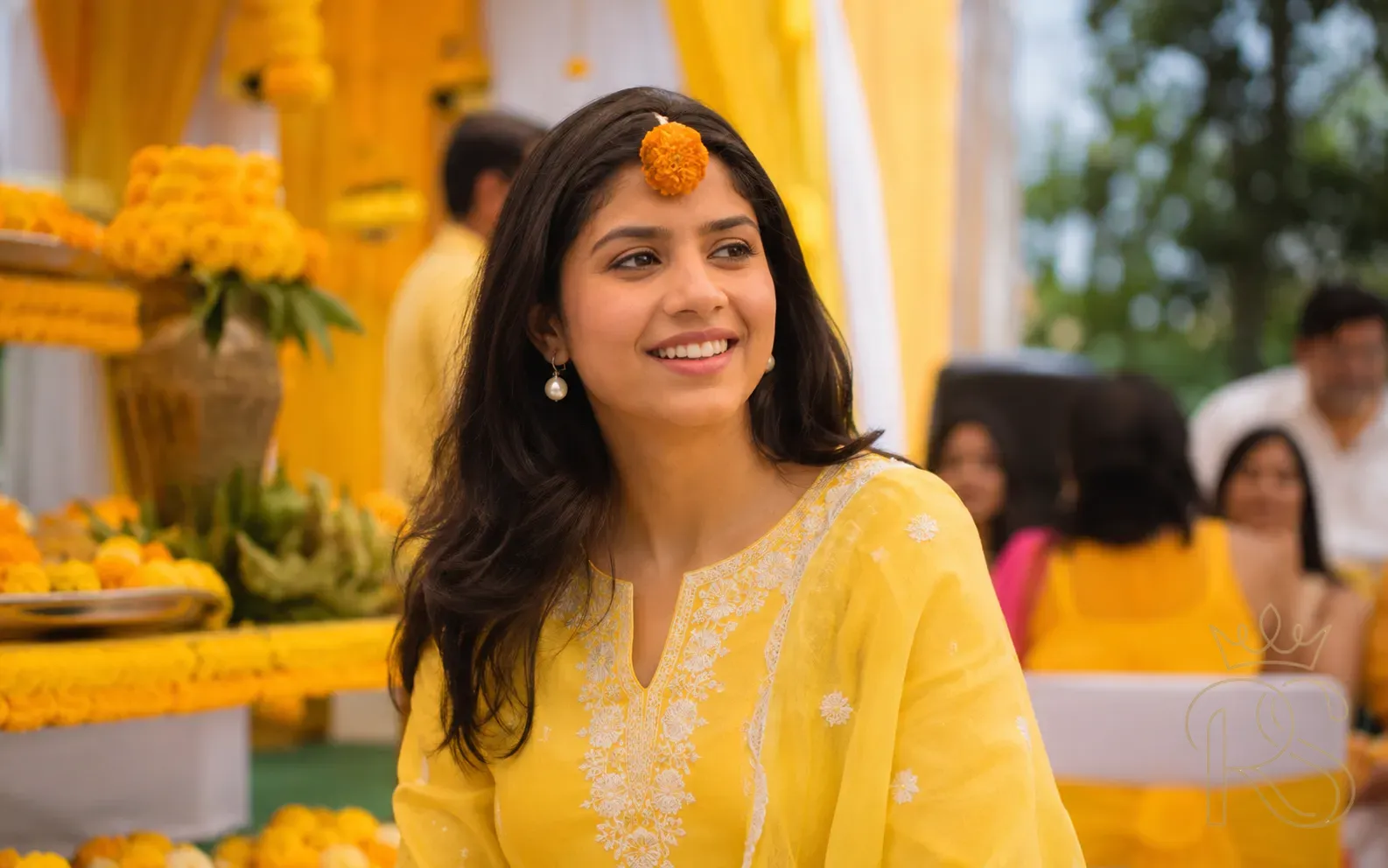 Indian wedding guest in yellow cotton salwar kameez with marigold flower hair accessory at Haldi ceremony