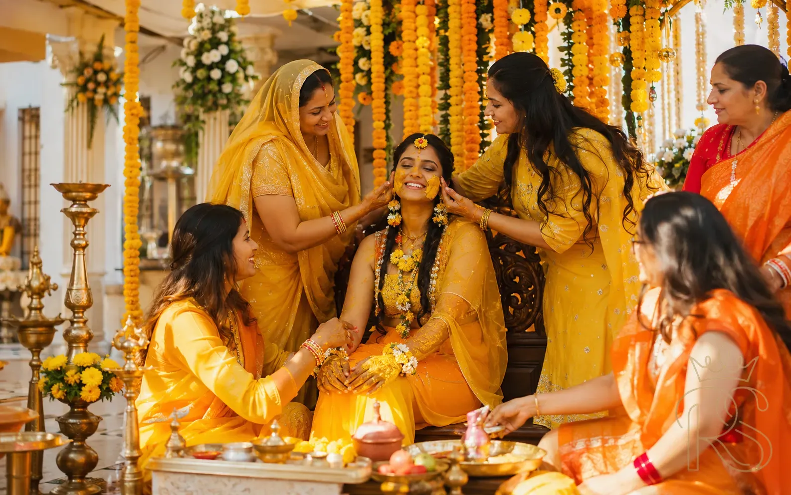 Indian bride seated on a decorated wooden manji under marigold canopy while female relatives apply haldi in morning light