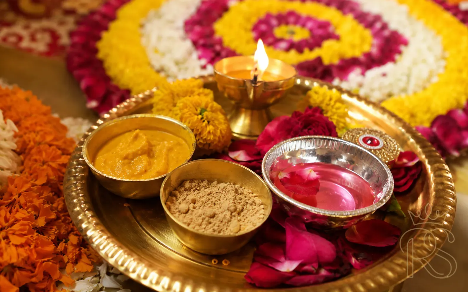 Brass thali with haldi paste, rose petals, marigold flowers and a diya arranged for the Haldi ceremony