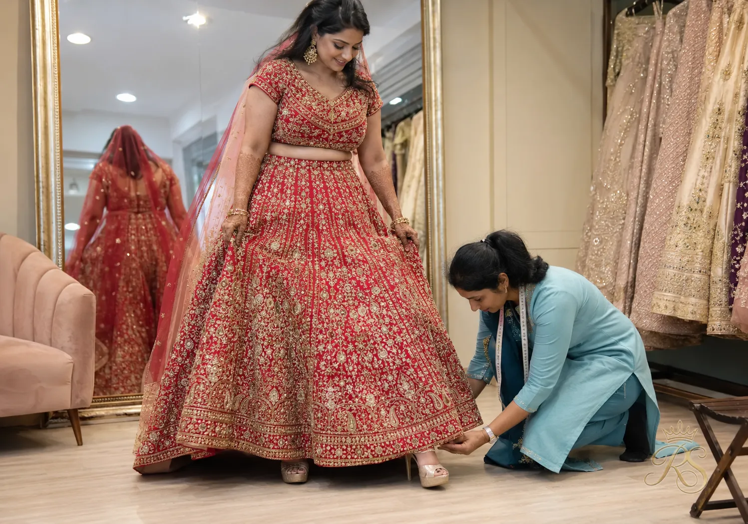Bride standing in her wedding heels while the hem of her lehenga is checked for length
