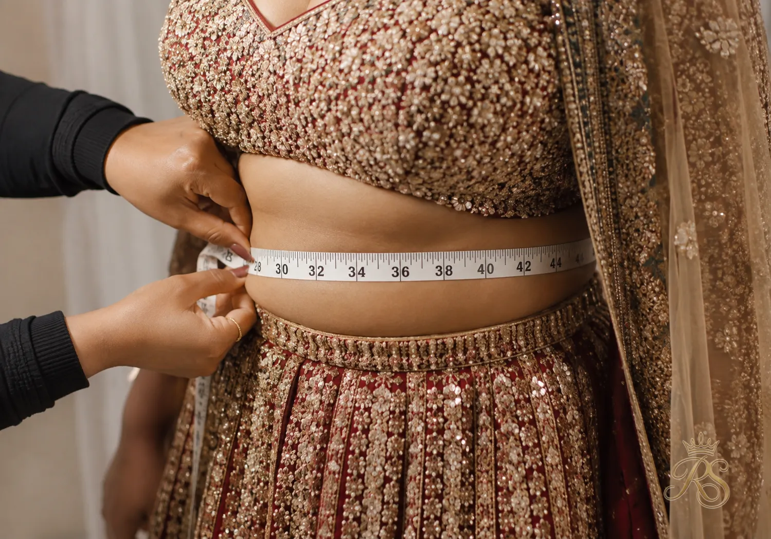Measuring tape wrapped around a bride's waist to record bridal lehenga measurements