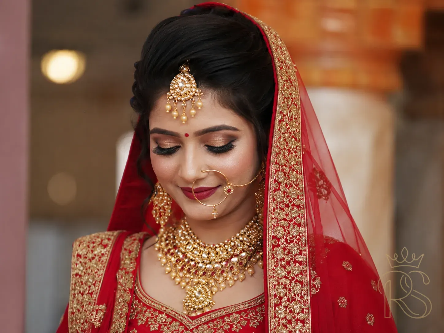Indian bride in traditional red lehenga with gold jewellery close up