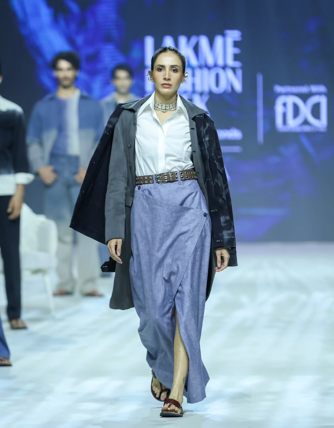 Male model on the runway in an indigo hand-embroidered khadi bandhgala jacket over a checked kurta, by Pawan Sachdeva