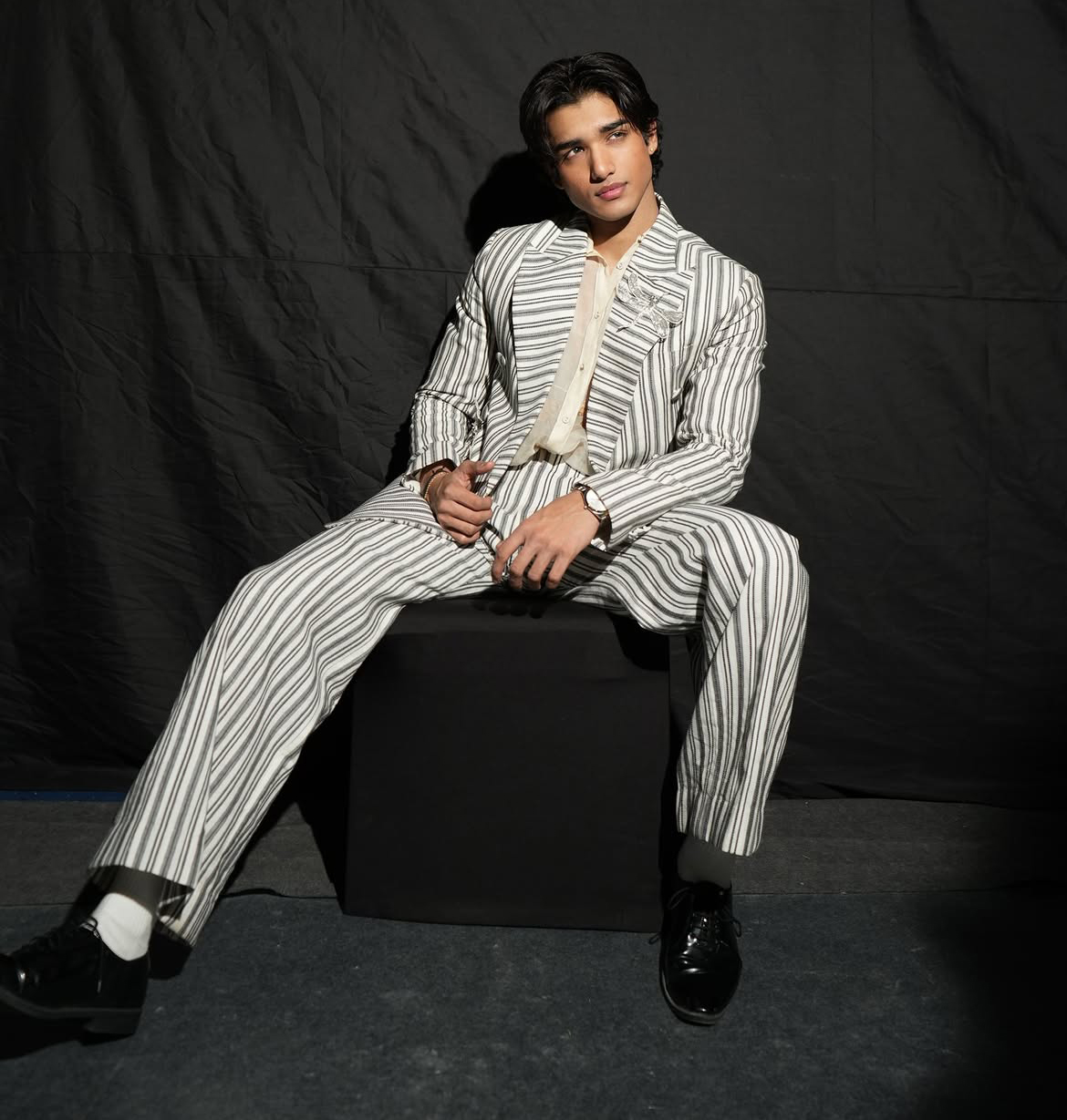 Male model backstage in a pinstriped suit with dragonfly embellishment ahead of the Rahul Mishra show