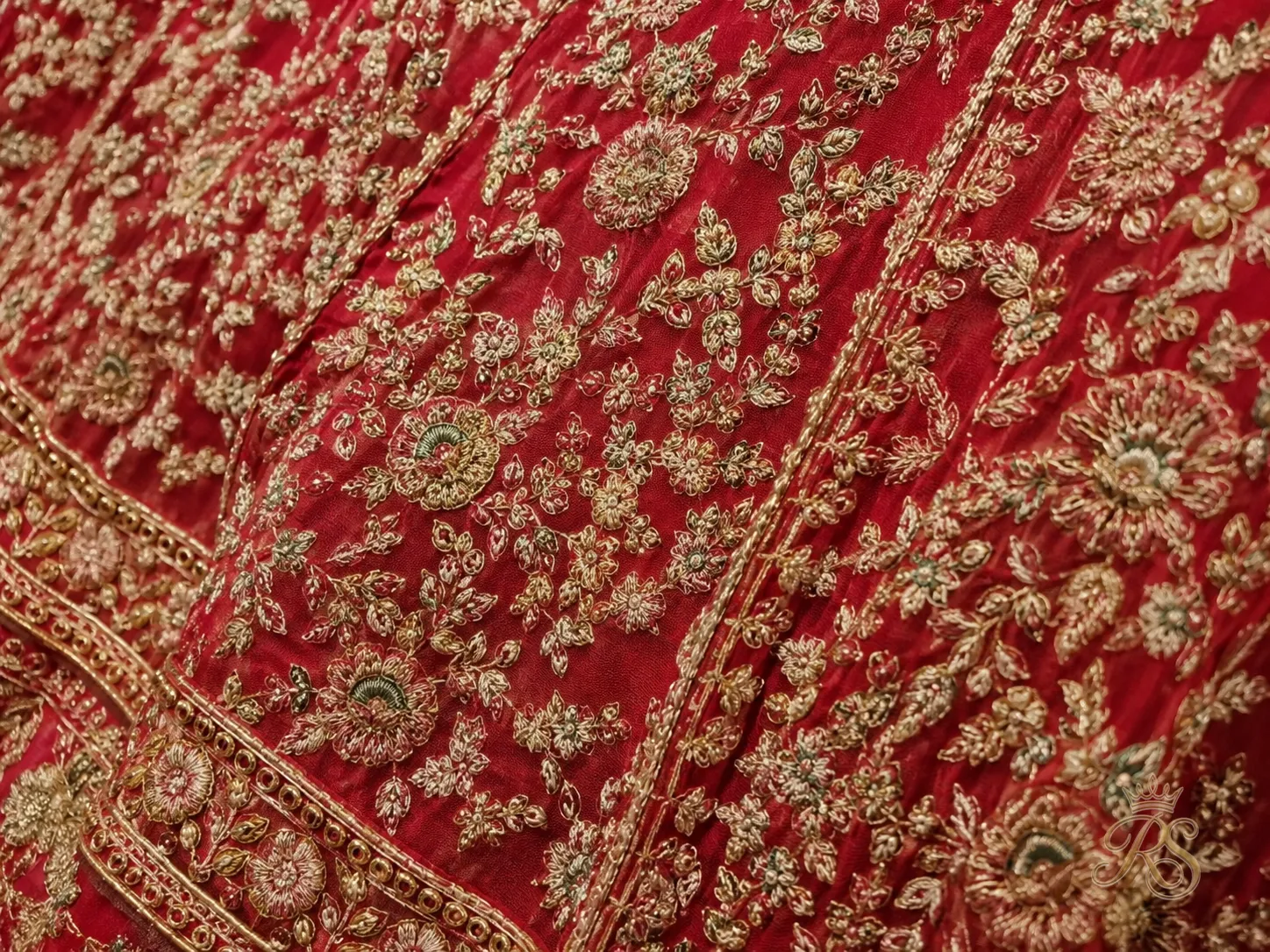 Hand-stitched vintage-style thread embroidery detail on red bridal lehenga