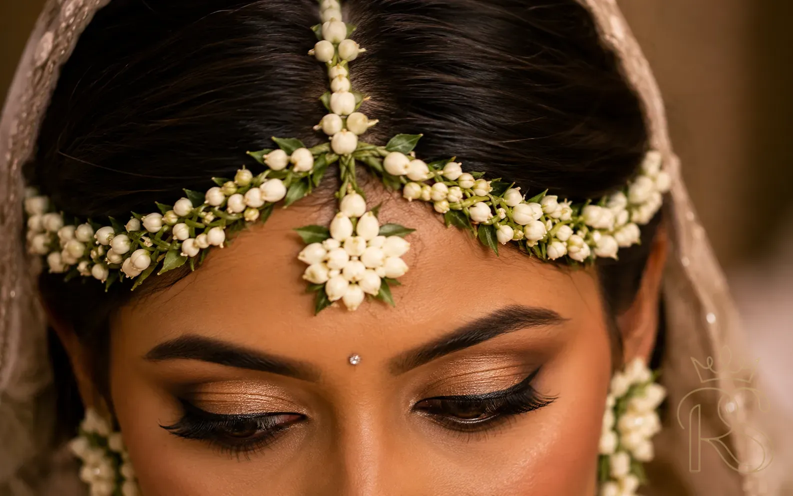 Close-up of Indian bride wearing intricate white jasmine flower matha patti forehead jewellery at Mehendi ceremony