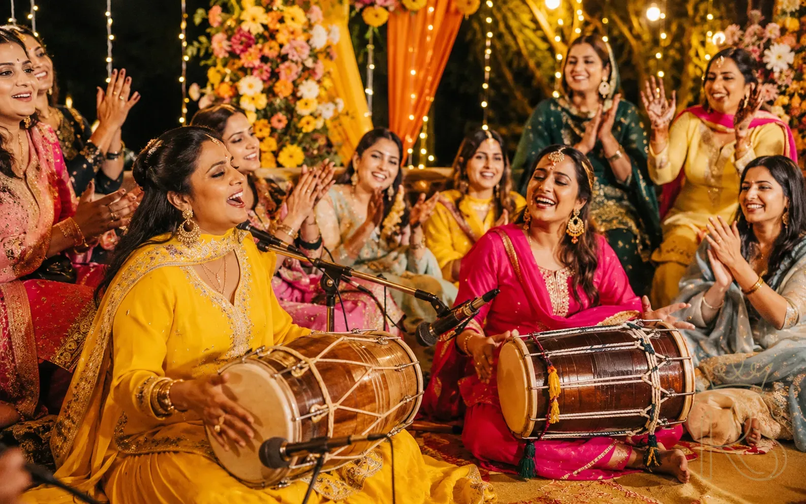 Live musicians playing dholak and singing Punjabi folk songs at Indian Mehendi ceremony night with guests clapping and dancing