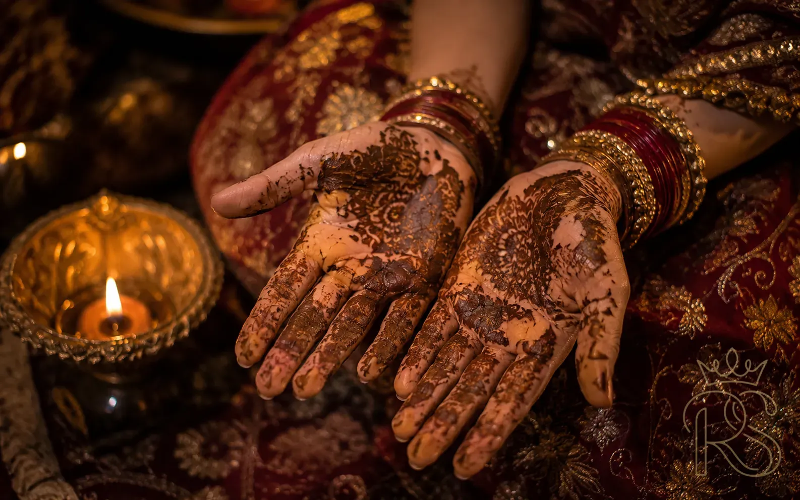 Indian bride's hands with dried cracking mehndi henna beginning to peel naturally in warm candlelit setting
