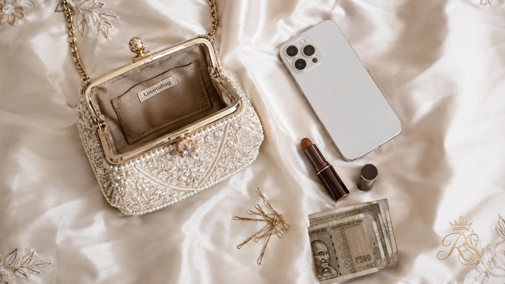 Flatlay of items that fit inside a bridal mini bag: phone, lipstick, pins and cash