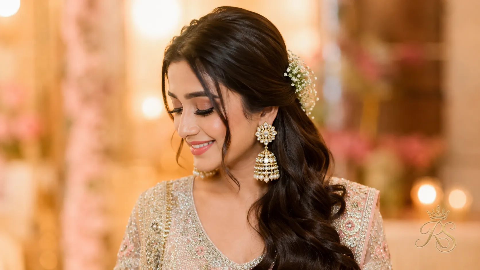 Bridal hairstyle swept to one side to showcase polki jhumka earrings