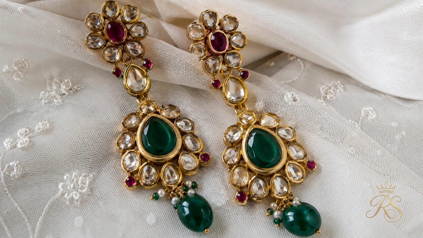 Detail shot of kundan drop earrings with ruby and emerald coloured stones