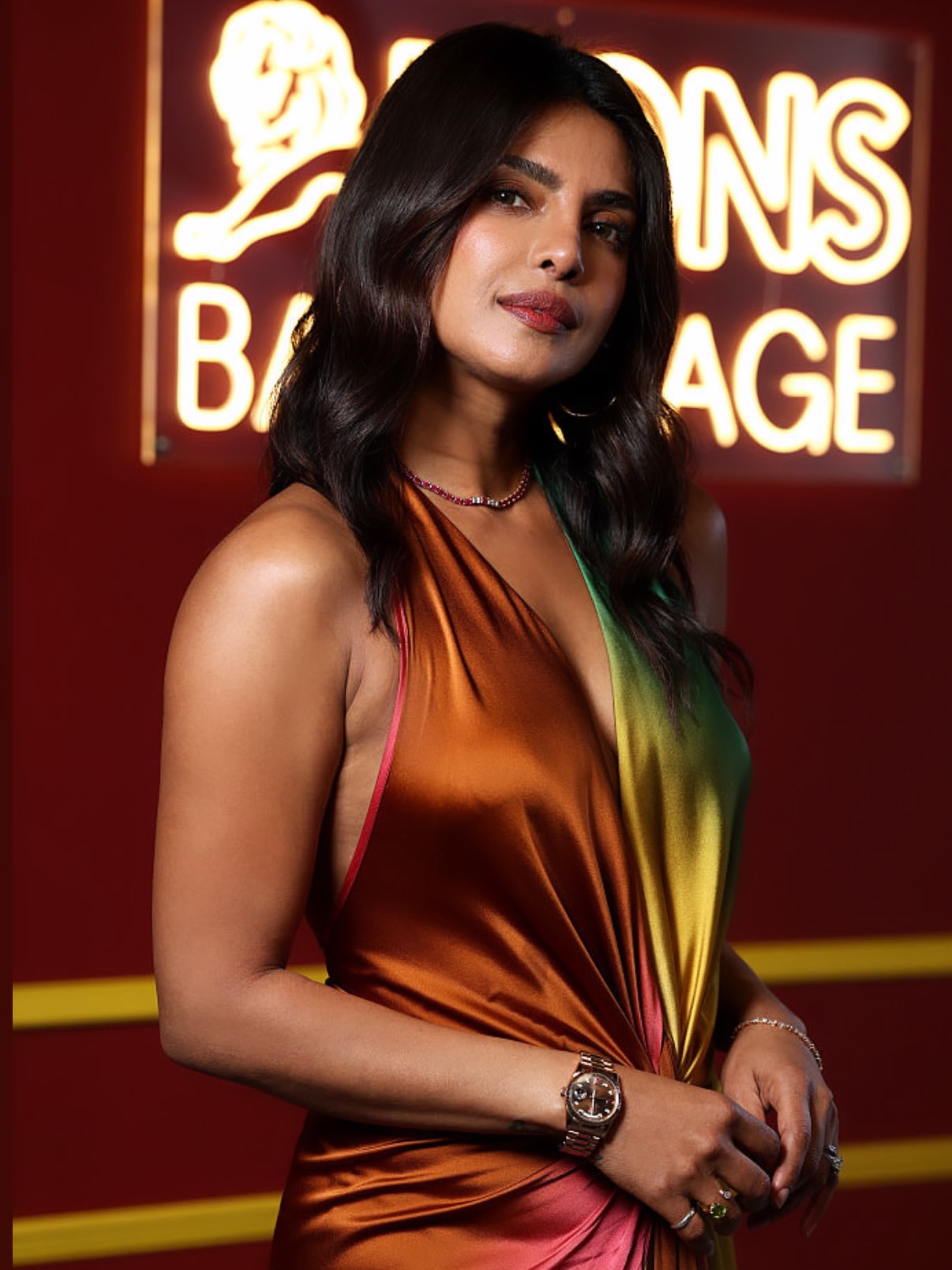 Priyanka Chopra in a silk halter dress in orange, pink and green tones backstage at a Cannes Lions event