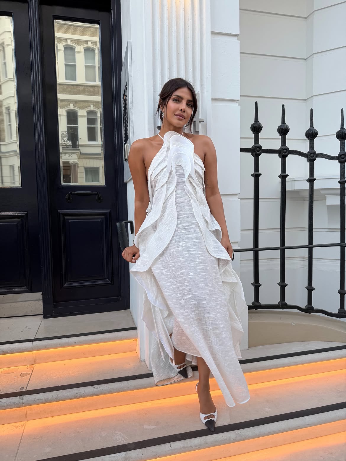 Priyanka Chopra in a white ruffled halter dress on a London street at dusk