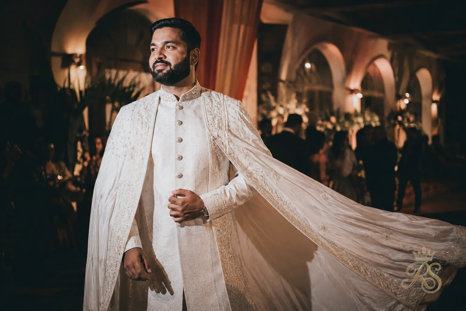 Groom in a dramatic draped cape-style sherwani for the wedding reception